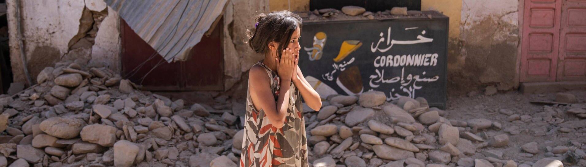 Ein Mädchen steht nach dem Erdbeben in Marokko in den Trümmern eines Hauses (Foto: dpa Bildfunk, picture alliance/dpa/AP | Mosa'ab Elshamy)