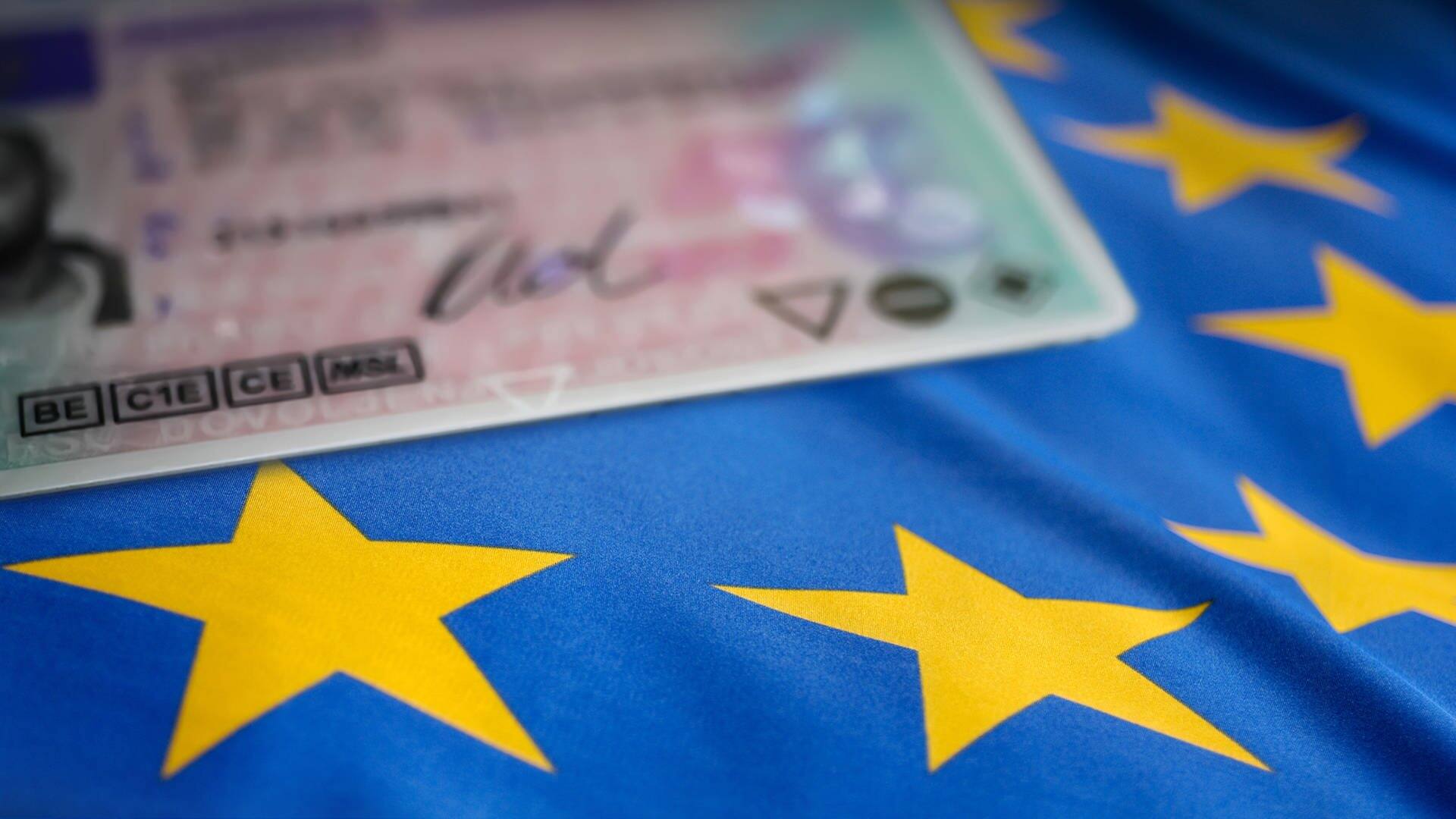 Ein Führerschein liegt auf einer Europaflagge. (Foto: Adobe Stock)