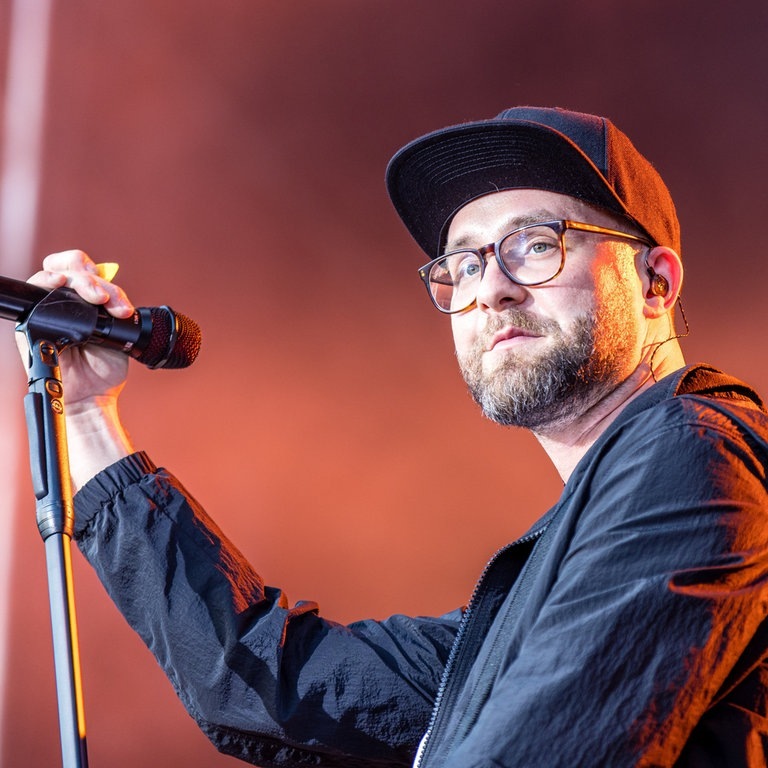 Sänger Mark Forster steht mit einem Mikofon in der Hand bei einem Konzert innerhalb seiner „Open Air Tour 2022“ auf der Bühne im Spreeauenpark.