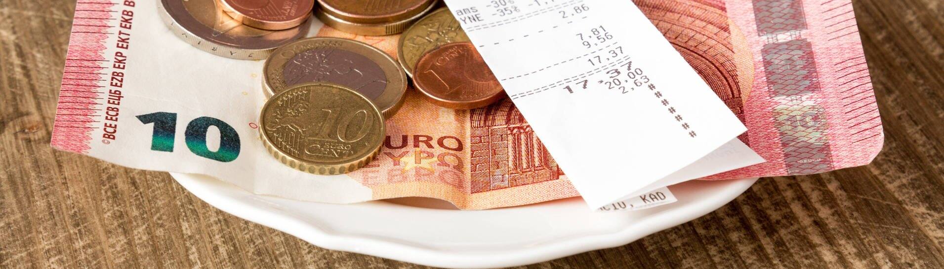 Geld liegt in einem Restaurant auf einem Teller. (Foto: IMAGO, IMAGO / Zoonar)
