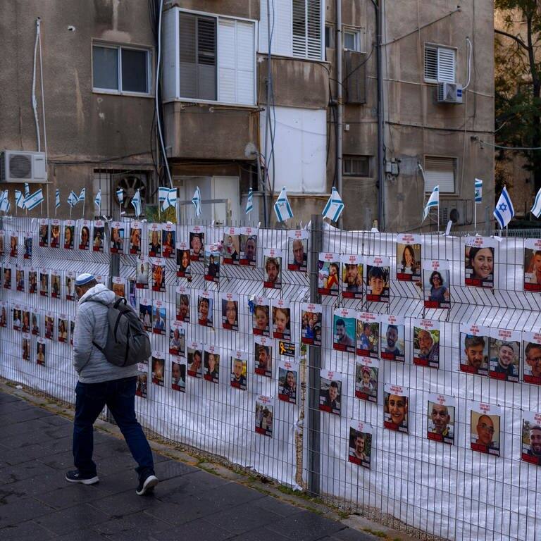 Ein Mann geht an einem Zaun mit Fotos von Geiseln vorbei, meist israelische Zivilisten, die während des Hamas-Angriffs auf Israel am 7. Oktober entführt wurden. (Foto: dpa Bildfunk, picture alliance/dpa/AP | Oded Balilty)