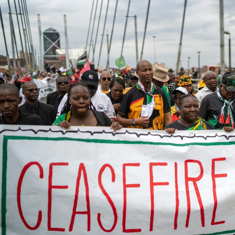 Pro-palästinensische Demonstranten marschieren über die Mandela-Brücke in der Innenstadt und hatlen ein Banner auf dem «CEASEFIRE NOW!» (Waffenstillstand jetzt!) geschrieben steht. Hunderte von Demonstranten protestierten gegen das israelische Vorgehen im Gazastreifen und forderten einen dauerhaften Waffenstillstand. (Foto: dpa Bildfunk, picture alliance/dpa/AP | Jerome Delay)