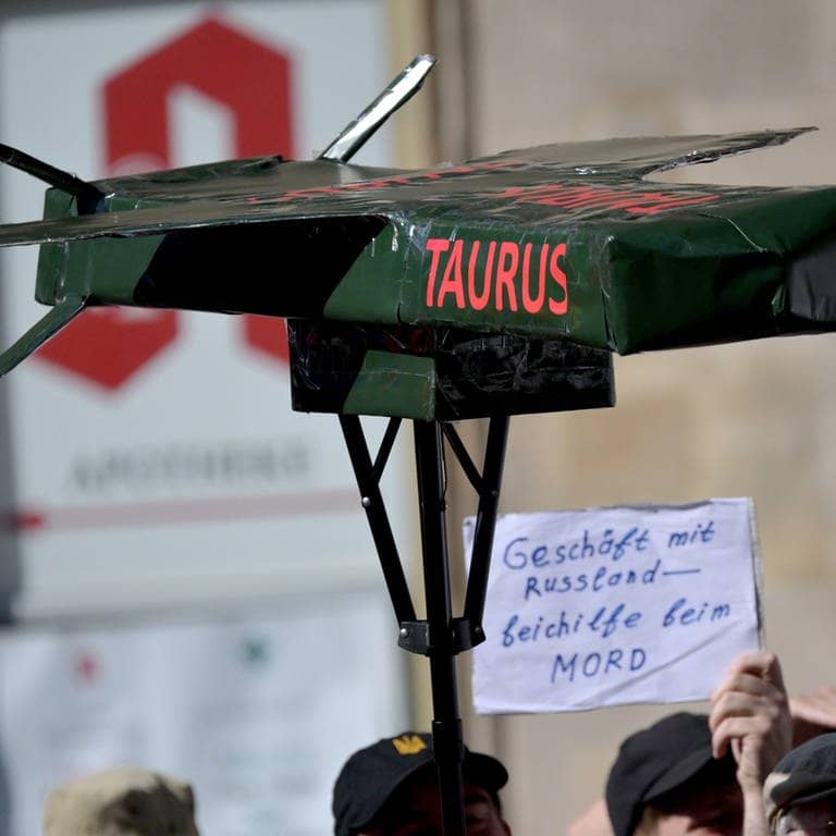 Protestierende halten bei einer Demo einen selbstgebastelten Taurus-Marschflugkörper in die Höhe (Foto: dpa Bildfunk, picture alliance/dpa | Peter Kneffel)