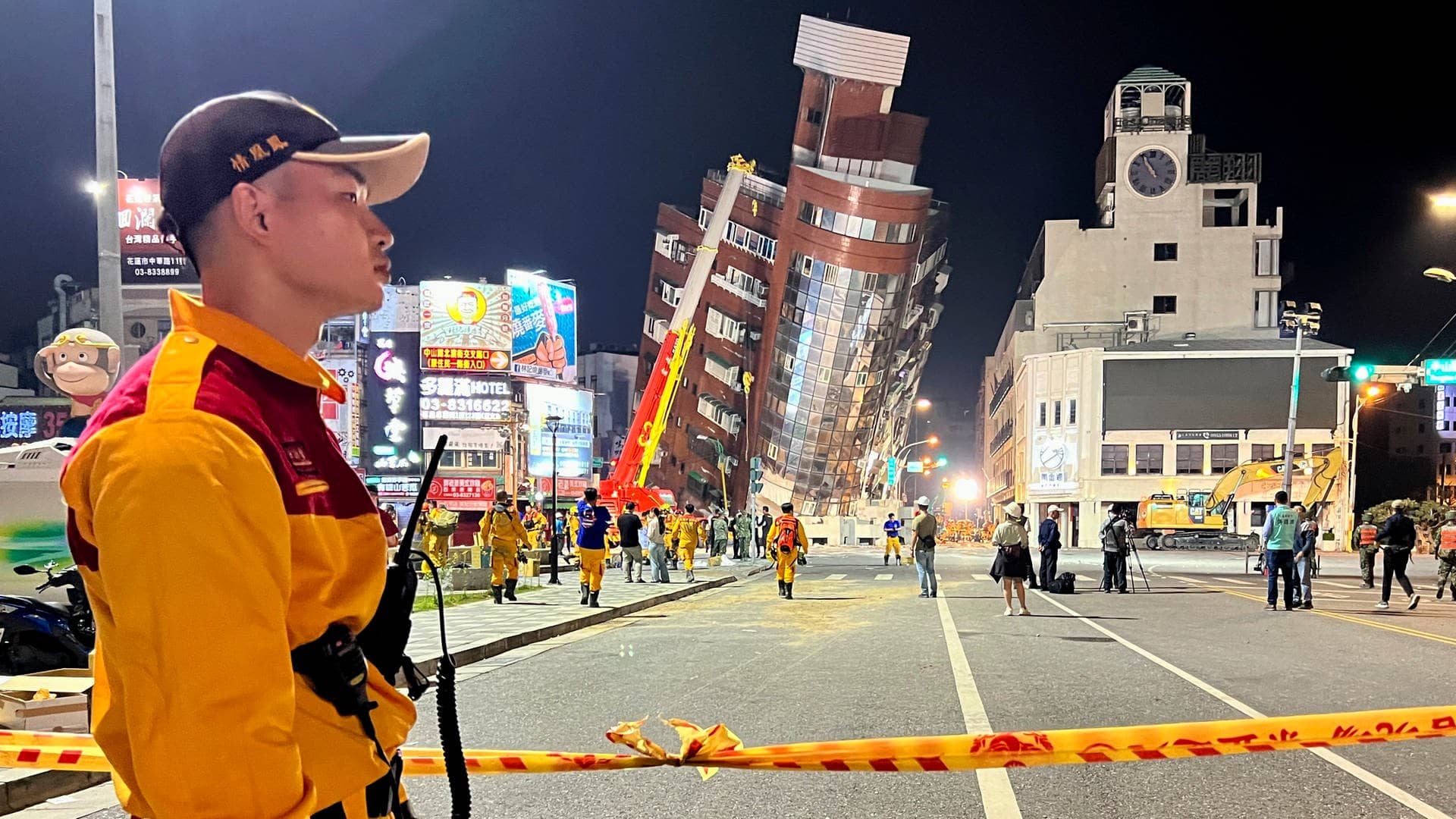 Ein Rettungshelfer steht in der Nähe der abgesperrten Stelle eines schiefen Gebäudes nach einem Erdbeben. 