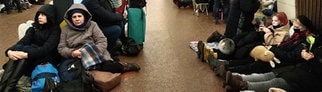 Menschen sitzen in einer U-Bahn-Station und nutzen diese als Bombenschutzraum.
