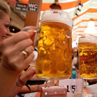 Menschen prosten sich zu mit einer Maß Bier auf dem Cannstatter Wasen 2019