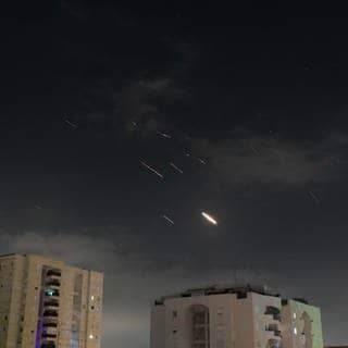 Flammen von Explosionen erscheinen am Himmel über Tel Aviv, während Israels Raketenabwehrsystem Raketen und Drohnen aus dem Iran abfängt. (Foto: dpa Bildfunk, picture alliance/dpa/JINI/XinHua | Tomer Neuberg)