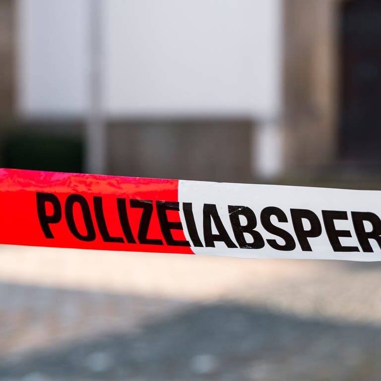 „Polizeiabsperrung“ steht auf einem rot-weißen Flatterband der Polizei. 