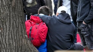 Nach Schüssen in Schule in Belgrad: Jugendliche sitzen an einem Baum und umarmen sich (Foto: dpa Bildfunk, picture alliance/dpa/AP | Darko Vojinovic) Nach Schüssen in Schule in Belgrad: Jugendliche sitzen an einem Baum und umarmen sich