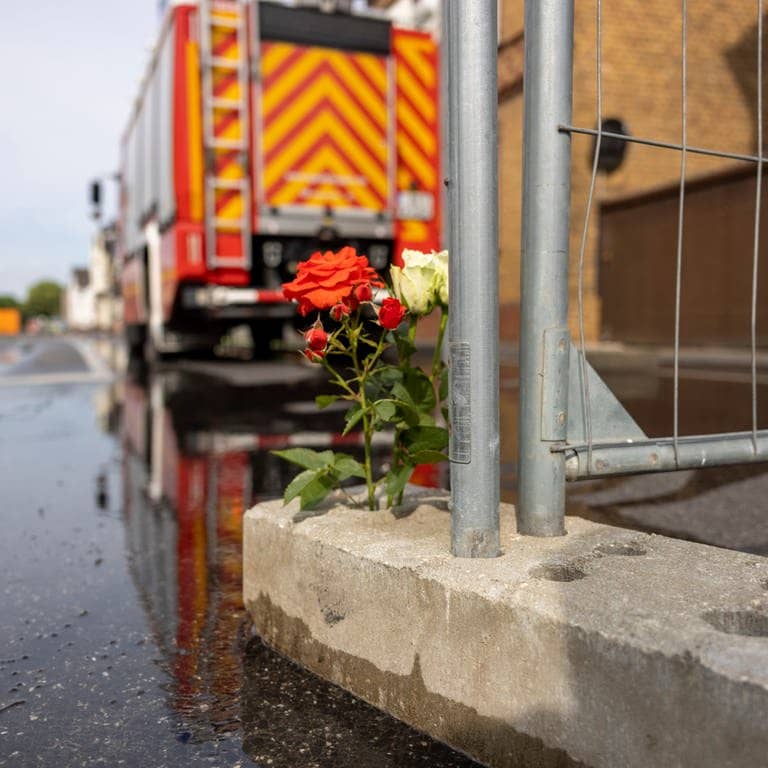 Blumen stehen an dem Absperrgitter in der Straße in Sankt Augustin, wo ein Motorradgeschäft brannte.