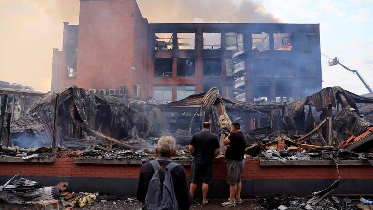 Passanten betrachten ein niedergebranntes Gebäude in der der Stadt Roubaix.