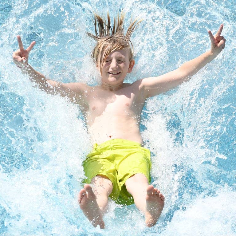 Ein Junge springt rückwärts in ein Schwimmbecken