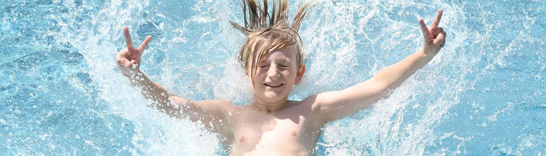 Ein Junge springt rückwärts in ein Schwimmbecken