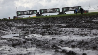 Banner mit der Aufschrift „Louder than hell“ vor einer matschigen Fläche