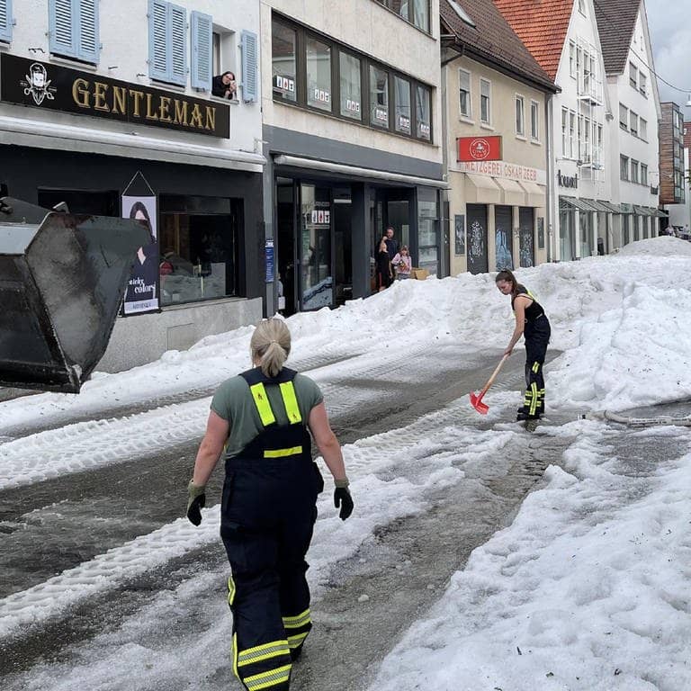 Einsatzkräfte der Feuerwehr räumen Hagel von einer Straße. Winterdienst-Einsatz mitten im Sommer: Ein lokal begrenztes Unwetter hat Straßen in der Innenstadt von Reutlingen mit einer hohen Hagel-Schicht überzogen.
