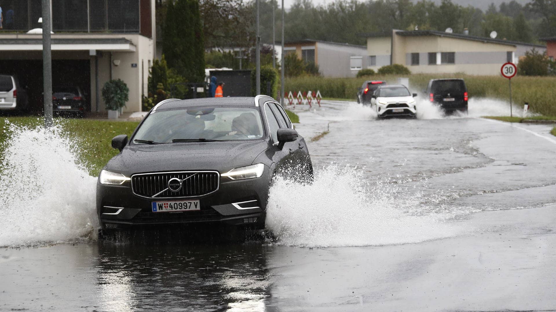 Ein Auto fährt über eine überschwemmte Straße bei Klagenfurt