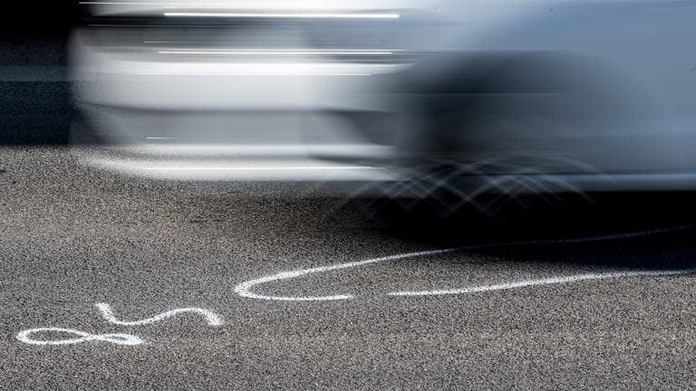 Symbolbild illegales Autorennen: Auto fährt über die Markierungen der Spurensicherung