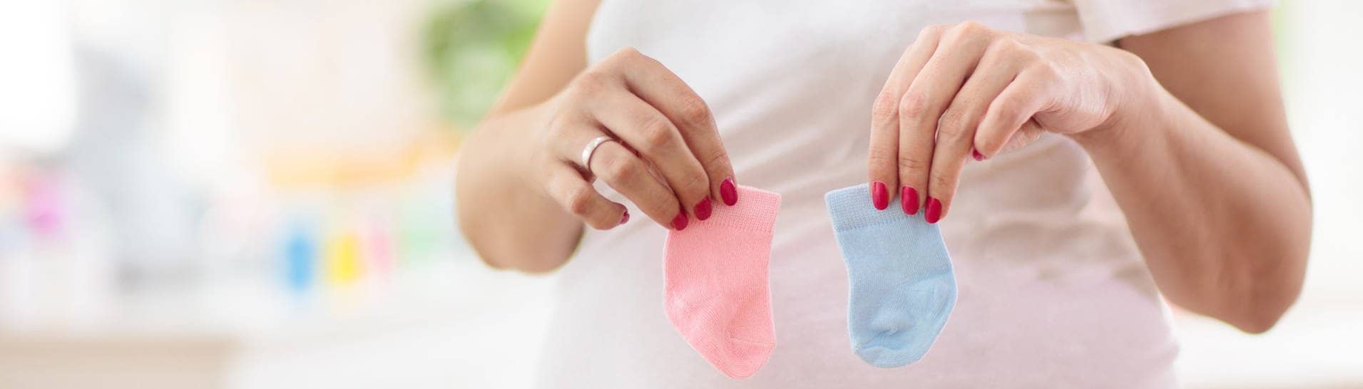 Gender Reveal: Schwangere Frau hält rosa und blaue Söckchen in der Hand (Foto: IMAGO, IMAGO / Pond5 Images)