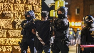 Ein Mann, der zu einer Gruppe von Menschen gehört, die nach Ausschreitungen bei einer Eritrea-Veranstaltung von Polizeikräften eingekesselt wurden, wird von Polizisten abgeführt.