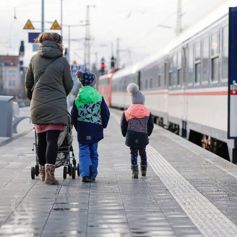 Eine Frau geht mit einem Kinderwagen und zwei Kindern über den Bahnsteig. (Symbolbild) 