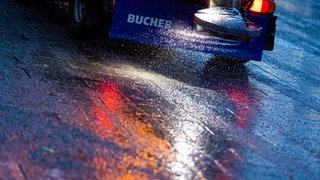 Ein Streufahrzeug streut Salz auf eine glatte Straße