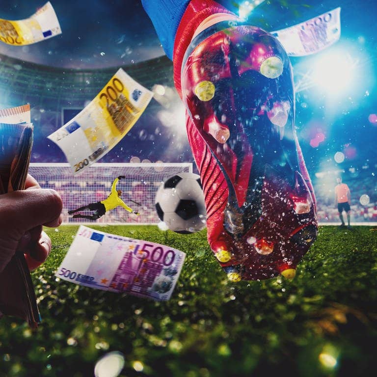 Füße eines Fußballers auf dem Rasen in Nahaufnahme, im Vordergrund hält jemand ein Bündel Geldscheine