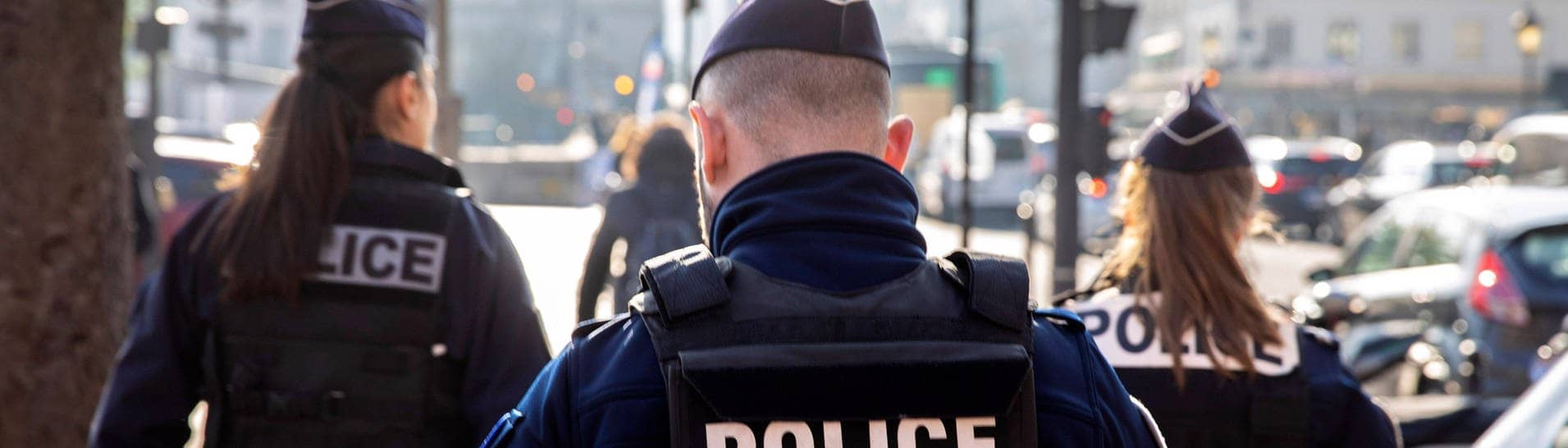 Polizeistreife der französischen Nationalpolizei. Man sieht drei Polizisten von hinten