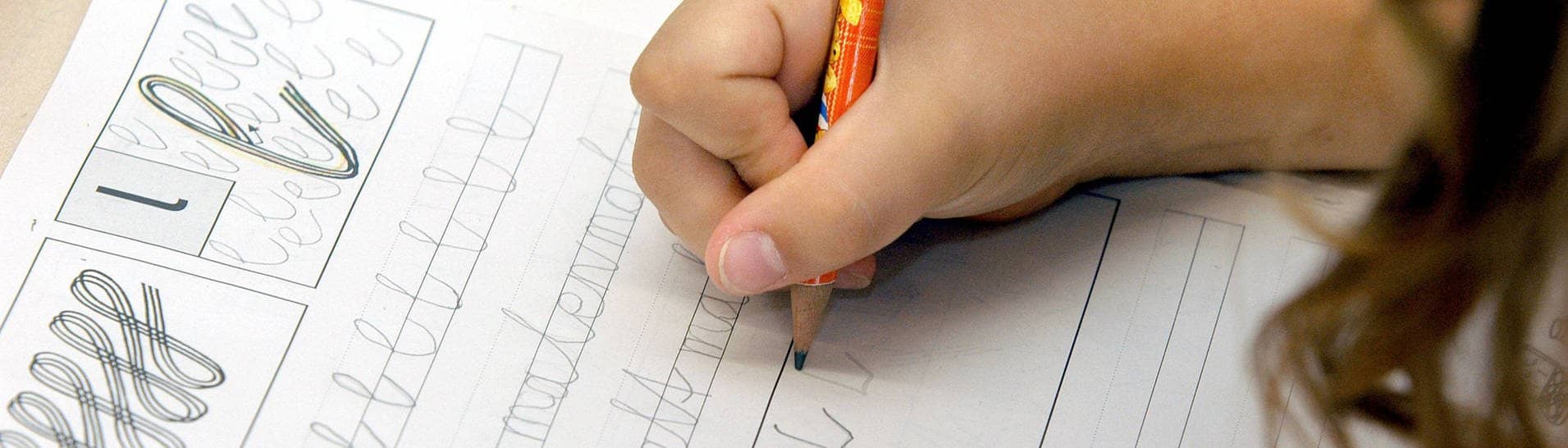 Ein Grundschulkind übt, ein L zu schreiben (Foto: IMAGO, imago/Marco Stepniak)