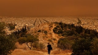 Roter Himmel, rote Erde: Ein Mann wandert am Dienstag in den Hügeln über Athen. (Foto: Reuters) Roter Himmel, rote Erde: Ein Mann wandert am Dienstag in den Hügeln über Athen.