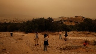 Menschen machen in den Hügeln über Athen Fotos. Hinten rechts im Bild sieht man die Akropolis. (Foto: Reuters) Menschen machen in den Hügeln über Athen Fotos. Hinten rechts im Bild sieht man die Akropolis.