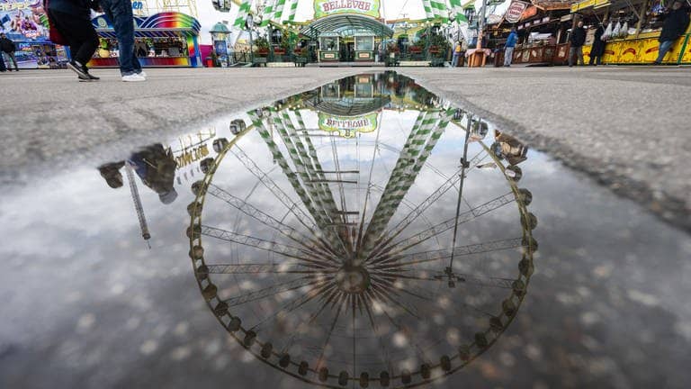 Ein Riesenrad spiegelt sich in einer Pfütze auf dem Festgelände des Stuttgarter Frühlingsfestes. (Foto: dpa Bildfunk, picture alliance/dpa | Marijan Murat)