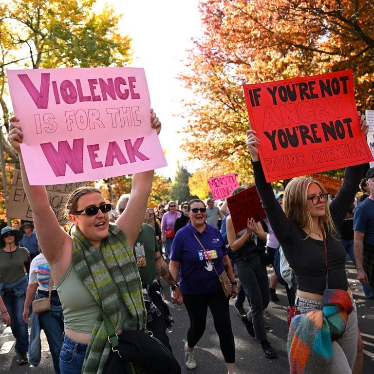 Demonstrierende halten Schilder hoch, als sie an einer Kundgebung zur Beendigung der Gewalt gegen Frauen in Canberra teilnehmen.
