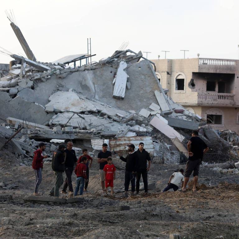 Gazastreifen: Palästinenser stehen vor einem zerstörten Viertel. (Foto: IMAGO, IMAGO / APAimages)
