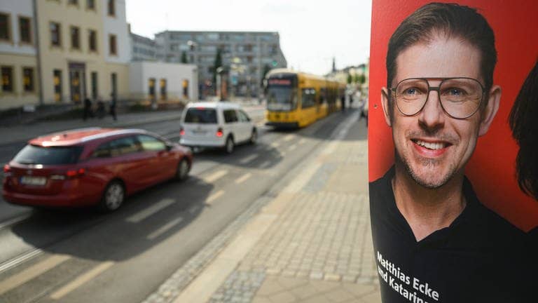 Ein Wahlplakat des SPD-Europabgeordneten, Matthias Ecke, der angegriffen wurde. Im Hintergrund sind Autos und eine Straßenbahn.