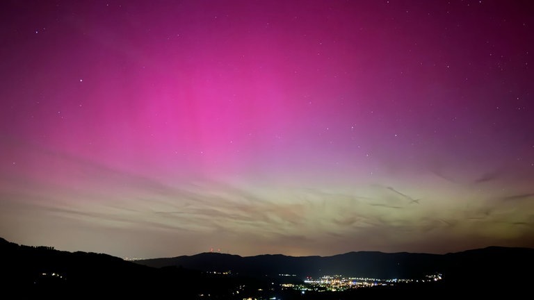 Rosa-grüne Polarlichter erscheinen über dem Dreisamtal im Schwarzwald bei Freiburg.