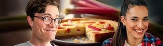 Bodo Wartke und Sally Özcan lächeln in Kamera. Im Hintergrund ist ein Rhabarberkuchen zu sehen.