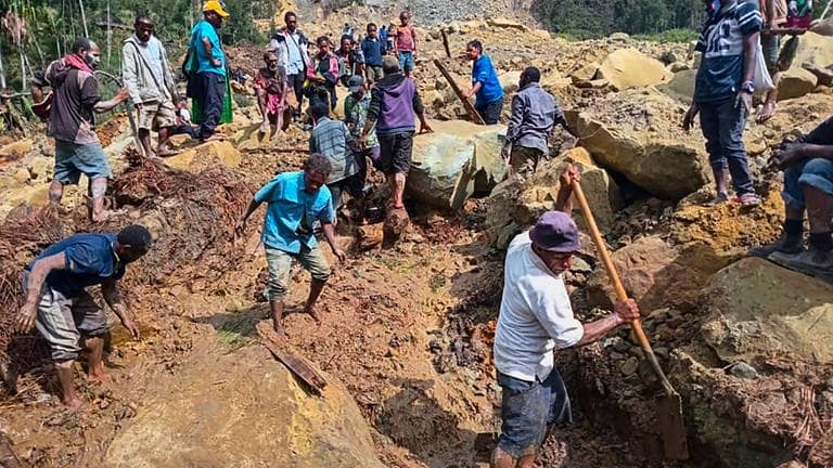 Auf diesem von der Internationalen Organisation für Migration zur Verfügung gestellten Foto suchen Dorfbewohner nach einem Erdrutsch im Dorf Yambali nach Verschütteten. 