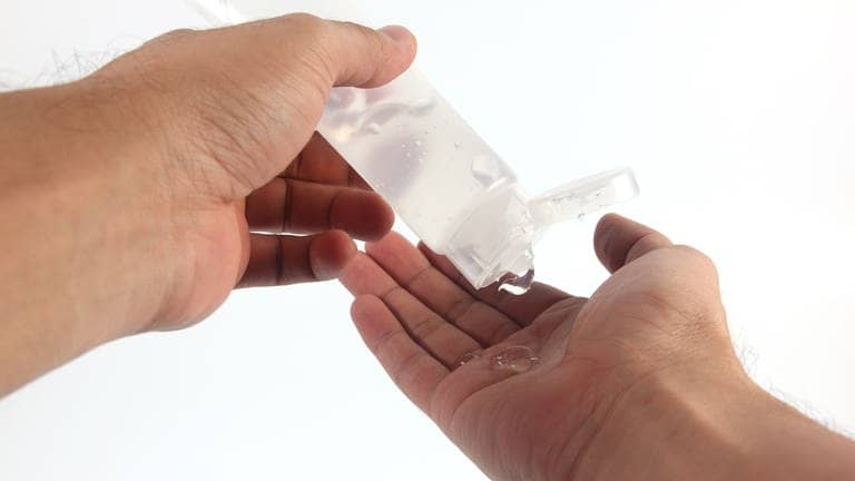 Eine Person drückt den Inhalt einer transparenten Tube auf ihre Hände