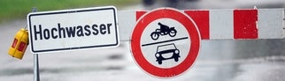 Ein Schild an einer Straßensperre warnt vor Hochwasser.