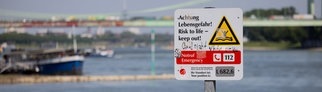 Ein Hinweisschild mit der Aufschrift "Achtung Lebensgefahr" weist am Rhein in Rodenkirchen auf die Gefahren beim Schwimmen in dem Fluss hin.
