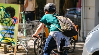 Ein Kind fährt mit Helm und Rucksack Fahrrad (Foto: IMAGO, imago images/Michael Gstettenbauer) Ein Kind fährt mit Helm und Rucksack Fahrrad