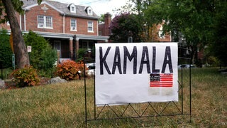 Ein handgefertigtes Schild mit der Aufschrift „Kamala“ und einer US-Flagge steht auf einem Rasen.