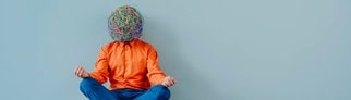 Neuer Trend Rawdogging: Ein Mann mit einem Korbgeflecht um den Kopf sitzt vor einer Wand und meditiert.