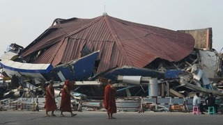 Erdbeben Myanmar: Buddhistische Mönche gehen nach einem starken Erdbeben an einem eingestürzten Gebäude vorbei.