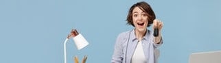 Symbolbild theoretische Führerscheinprüfung mit neuen Fragen vom 1. April 2025: Frau hält lachend einen Autoschlüssel in der Hand