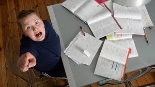 Ein Junge sitzt am Tisch für seine Hausaufgaben