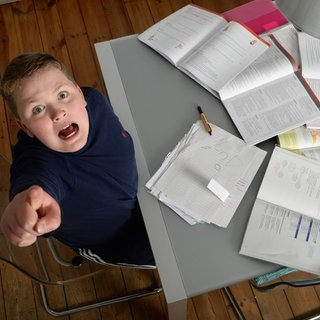 Ein Junge sitzt am Tisch für seine Hausaufgaben