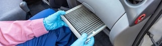 Jemand zieht einen Pollenfilter aus dem Auto. Einmal jährlich sollte man den wechseln.