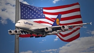Ein Flugzeug der Lufthansa vor einer Flagge der USA. Symboldbild für die Einreisebestimmungen.