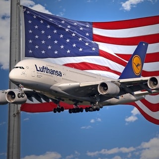 Ein Flugzeug der Lufthansa vor einer Flagge der USA. Symboldbild für die Einreisebestimmungen.